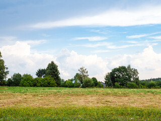 gray and white clouds in blue sky over mowed field after summer rain