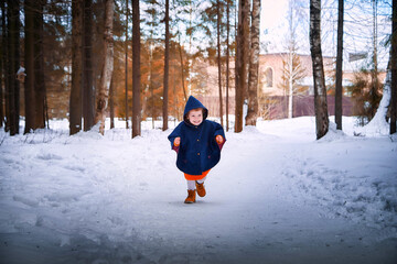 Fototapeta na wymiar Stylish happy kid girl 2-3 year old with redhair wear blue coat and yellow scarf walk in city street in winter, autumn or spring season with snow