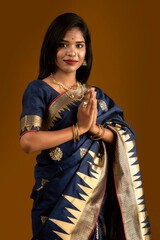 Portrait of a beautiful Indian girl in a greeting pose to Namaste hands. India woman in traditional saree.