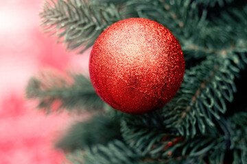 New Year's toy, a ball, on a Christmas tree. Christmas tree with red ball close-up