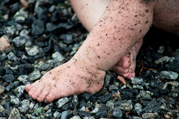 close up of dirty baby feet and legs while baby plays in the rocks