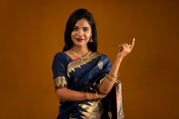 Portrait of a cheerful young girl or woman pointing something with a happy smiling face.