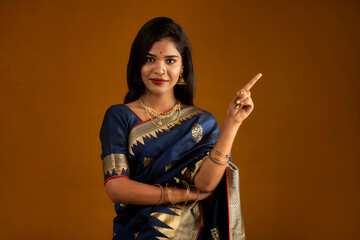 Portrait of a cheerful young girl or woman pointing something with a happy smiling face.