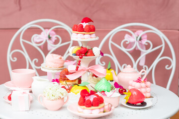 Big assortment of pink sugar dessert treats on white table in cafe or candy shop. Holiday celebration with tasty food