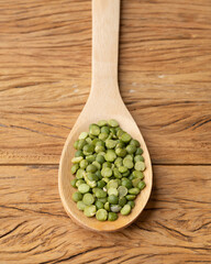 Raw dried green peas in a spoon over wooden table
