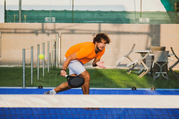 Padel match in a blue grass padel court - Handsome boy player playing a match