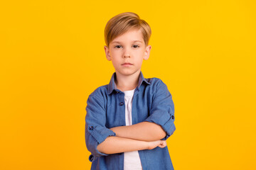 Portrait of focused calm school boy crossed arms serious look isolated on yellow color background