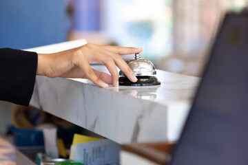 Ring bell call service with hand on hotel reception desk