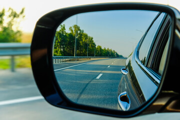Look in the rear view mirror of a car. Car driving on the road.