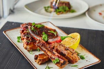 Grilled meat ribs with lemon. The cook's hand roasts the meat with fire. A dish from the chef for serving in a restaurant.