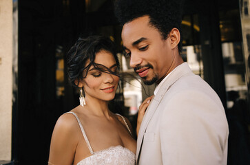 Naklejka premium Stylish stunning couple together on their wedding day against the backdrop of a city hotel. Luxury wedding of a beautiful couple