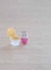 little toy cat and toy toilet bowl close up on abstract blurred beige background. kids potty training concept.