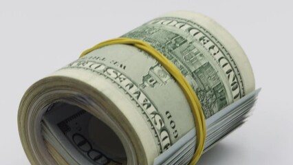 Bundle of money roll of dollars isolated on white background, stack of one hundred dollars American cash money bills rolled up with rubber band.