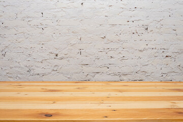 Wooden table made of planks on the background of a white texture of a brick wall for design. A place for your text or image.