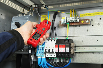 Electrician engineer work tester measuring voltage and current of power electric line in electical...