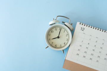 close up of calendar and alarm clock on the blue table background, planning for business meeting or travel planning concept