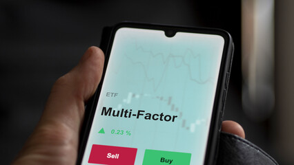 An investor's analyzing the multi factor etf fund on a screen. A phone shows the prices of...