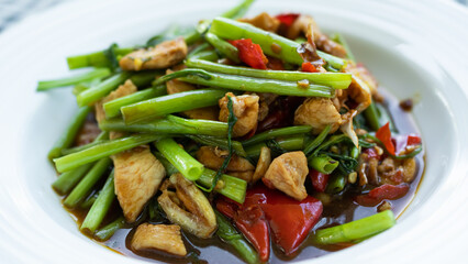 Stir-Fried Chinese Morning Glory with chicken in white plate background.traditional food asian Thailand.Hot and spicy. Food for good health and diet.'