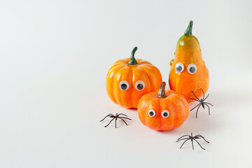 Pumpkins with eyes and spiders on white background. Minimal Halloween funny concept. Freaky autumn...