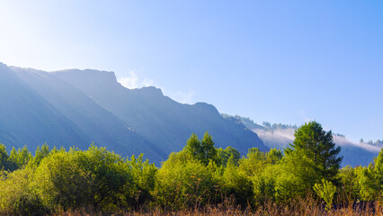 Sunny summer landscape with light haze and fog over the far 