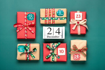 Xmas advent calendar concept Handmade wrapped red, green gift boxes decorated with ribbons, snowflakes and numbers, Christmas decorations and decor on green table Top view Flat lay Holiday card