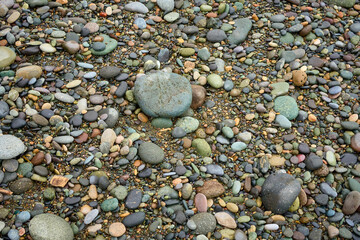 Abstract background texture of random sizes of stones and colored smooth pebbles on the seashore