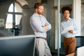 Black entrepreneur and her colleague going through business reports in office.