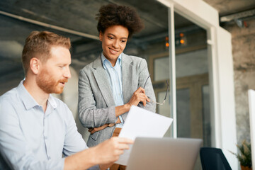 Happy black CEO and he colleague going through reports in office.