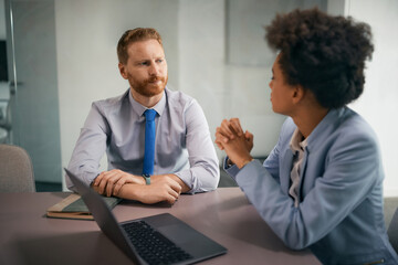 Obraz premium Mid adult businessman having meeting with black female colleague in office.
