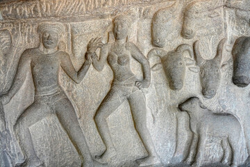 Human rock relief sculptures carved in the rock cut ancient cave temple in Mahabalipuram, Tamilnadu. Indian rock art of bas relief human sculptures at rock cut historical monolithic cave in Tamilnadu.