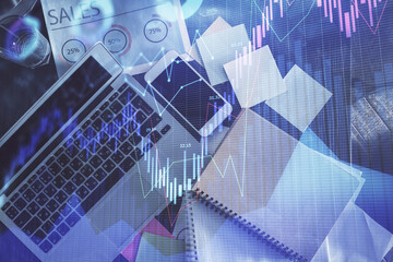 Financial market graph and top view computer on the desktop background. Multi exposure. Investment concept.