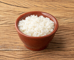 Cooked white rice in a bowl over wooden table