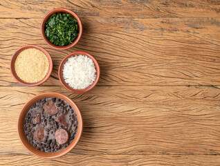 Fototapeta na wymiar Typical brazilian feijoada with farofa, rice, kale and copy space