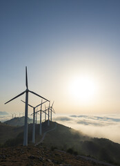 Wind turbines at Korneita wind farm with the sun above the clouds, Spain
