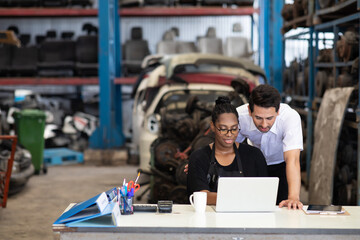 African American female worker and man customer choose and inspecting car part products while working in a old car part warehouse store.