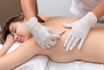 Fototapeta premium young woman lying on a stretcher in an aesthetic center performing beauty treatment and facial aesthetics with dermapen and dermaplaning techniques