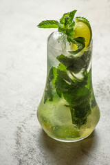 Mojito cocktail with lime and mint in highball glass on a grey stone background .