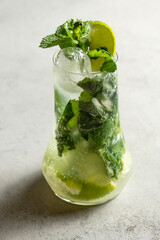 Mojito cocktail with lime and mint in highball glass on a grey stone background .