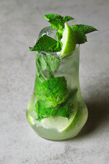 Mojito cocktail with lime and mint in highball glass on a grey stone background .