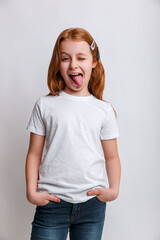 Portrait of funny kid girl smiling and showing tongue in camera wearing in white t-shirt. Close-up kid portrait