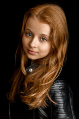 Naklejka premium Close-up portrait of a adorable little girl with long red hair on black studio background. Fashion kids model