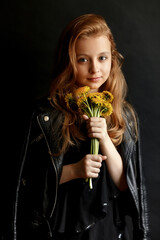 portrait of a pretty little girl with long red hair holding a bouquet of dandelions on black background