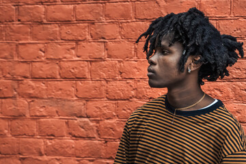 Young handsome stylish black man with natural hair dreadlocks. Afroamerican guy.Stairs,wall painted with graffiti in poor quarter of street art culture city district.African american skateboarder man