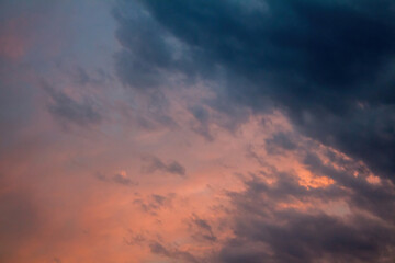 Fototapeta na wymiar Sunset sky with dark blue clouds through which the rays of the sun break through