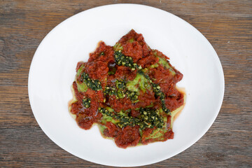 Pasta. Top view of spinach ravioli with tomato sauce and pesto, in a white dish.