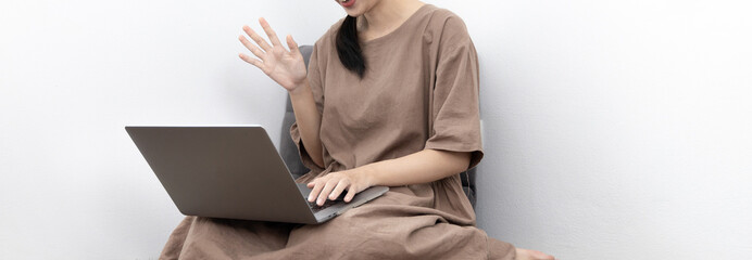Young Asian woman happily using her laptop to chat or talking with her friends, Entertaining or relaxing using computer technology, Stay at home for long weekend, Happy lifestyle.