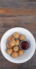 	
Fritters. Top view of potato and mozzarella cheese croquettes with sweet chili dipping sauce, in a white bowl on the wooden table.
