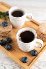 Blurred image on a tray of two cups of espresso, cookies and blueberries.