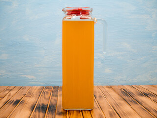 Orange juice in a jug. Glass pitcher and orange juice on a wooden table.