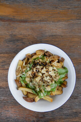 French fries. Top view of a bowl with fried potatoes with spinach cream, mozzarella, cheddar, danvo and blue cheese, in a white bowl on the wooden table.